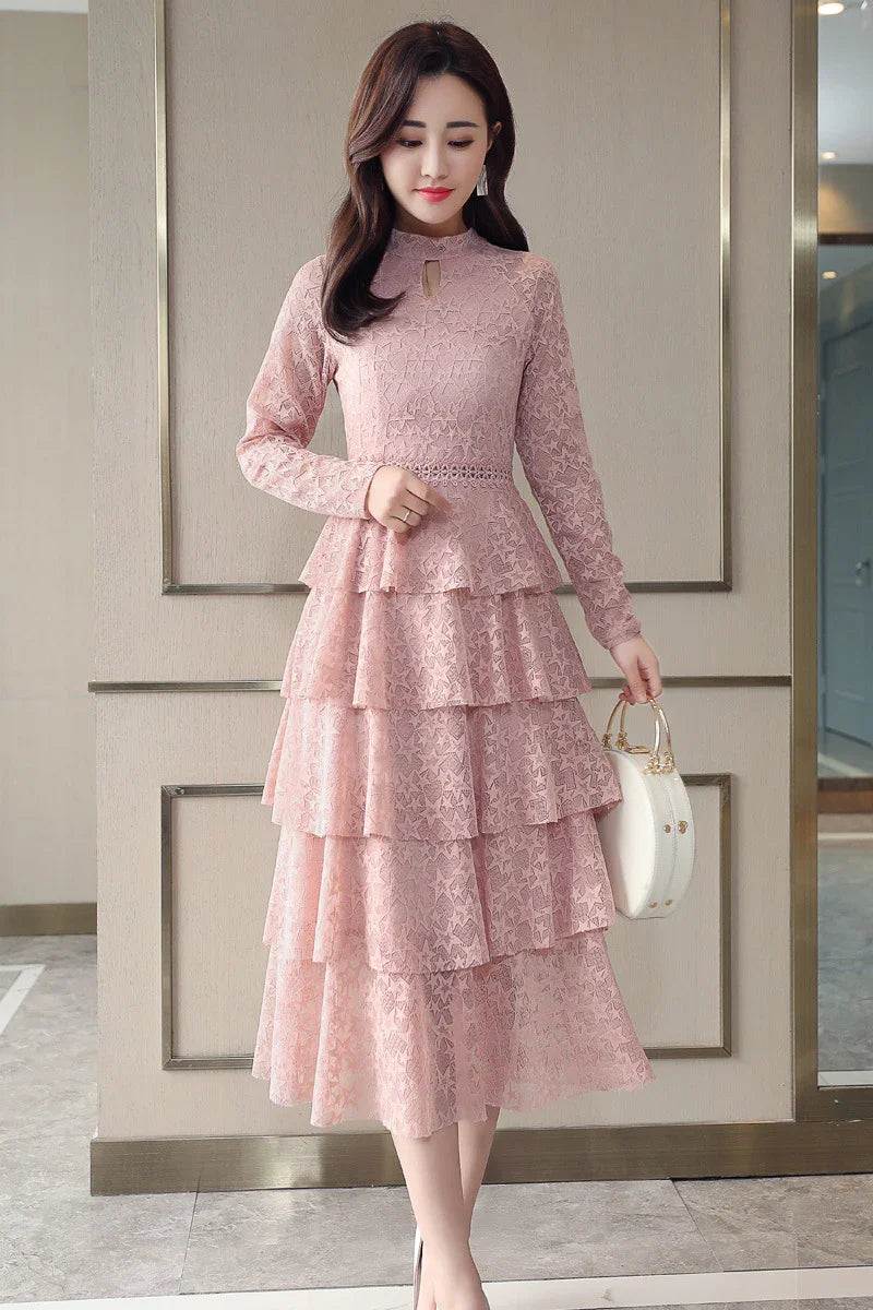 Pink lace maxi dress with tiered ruffles, long sleeves, and keyhole neckline, paired with white handbag