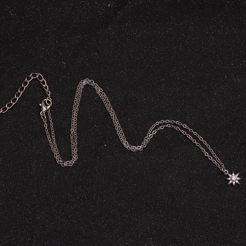 Delicate silver chain necklace with sparkling star pendant on black textured background