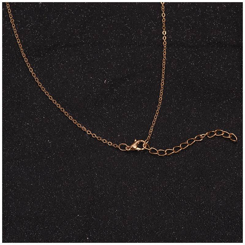 Delicate gold chain necklace with lobster clasp and adjustable extender on dark textured background