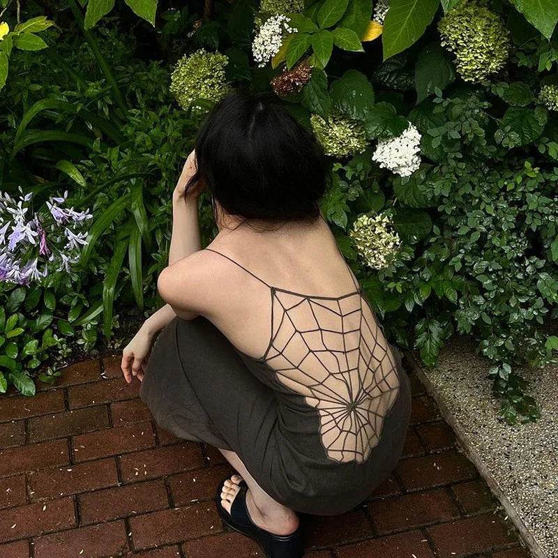 Woman in backless spiderweb top crouching in garden with hydrangeas, stylish summer lingerie