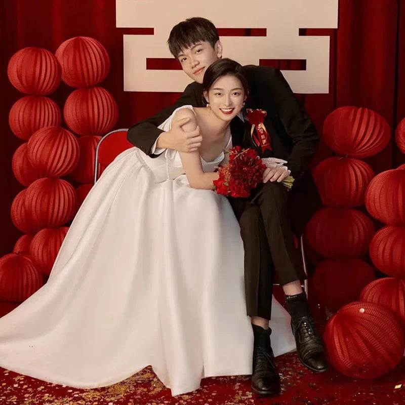 Bride in white wedding gown with groom, red lanterns, and festive backdrop for elegant celebration