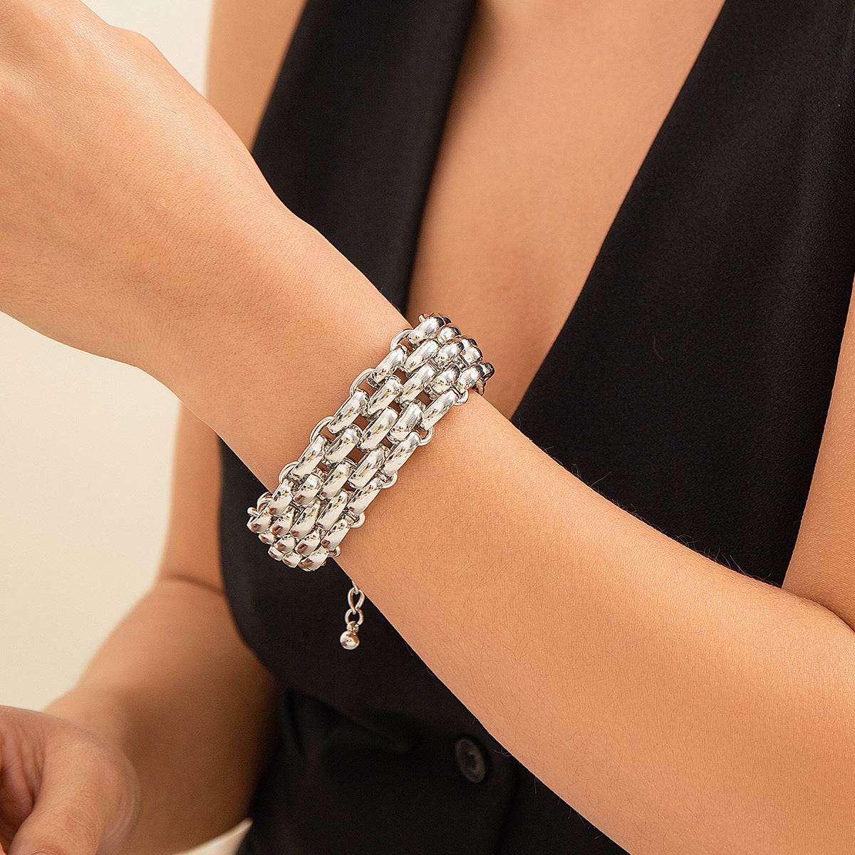 Elegant silver chain-link bracelet with dangling charm, styled on wrist with black outfit