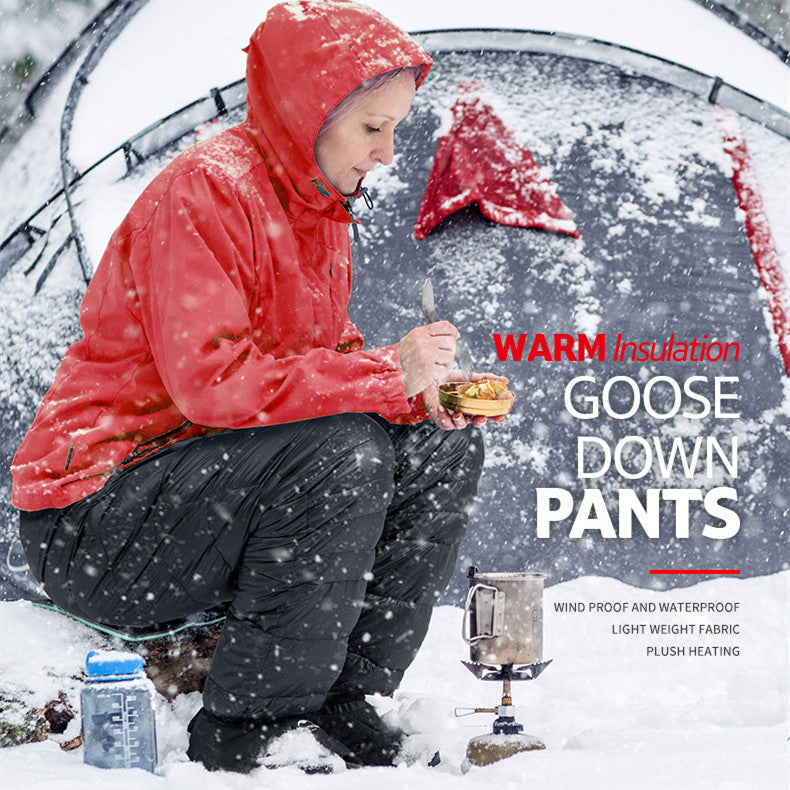 Laylace black goose down puffer pants worn by a woman camping in the snow, featuring a water-resistant nylon shell.