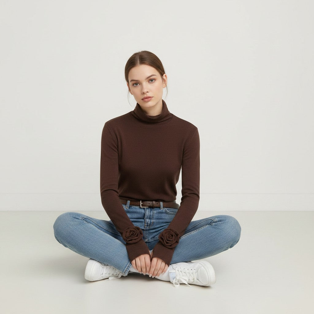 Laylace brown long sleeve turtleneck top with 3D rose floral cuffs worn by a woman sitting in jeans and sneakers