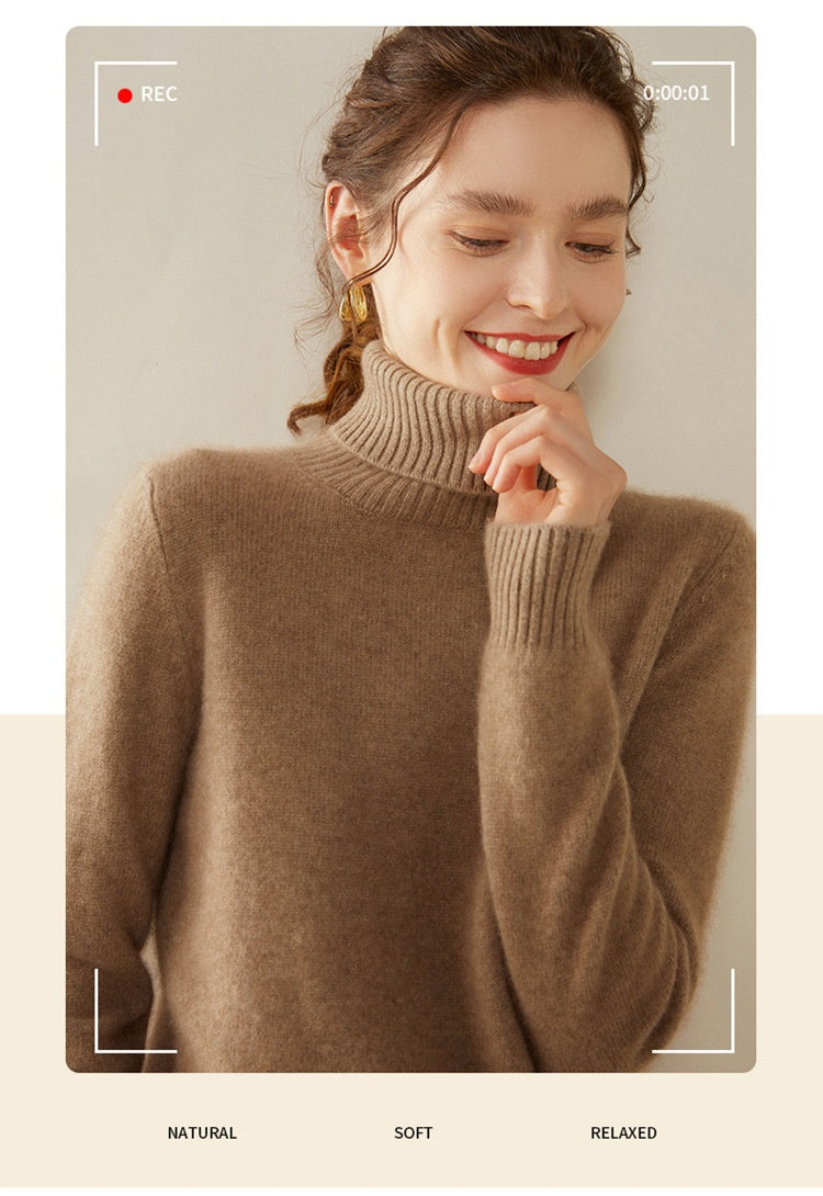 A smiling woman wearing a thick camel-colored Laylace cashmere turtleneck sweater with a ribbed high neckline.