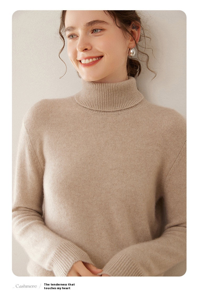 A smiling woman wearing a thick camel-colored Laylace cashmere turtleneck sweater with a soft, cozy knit texture.