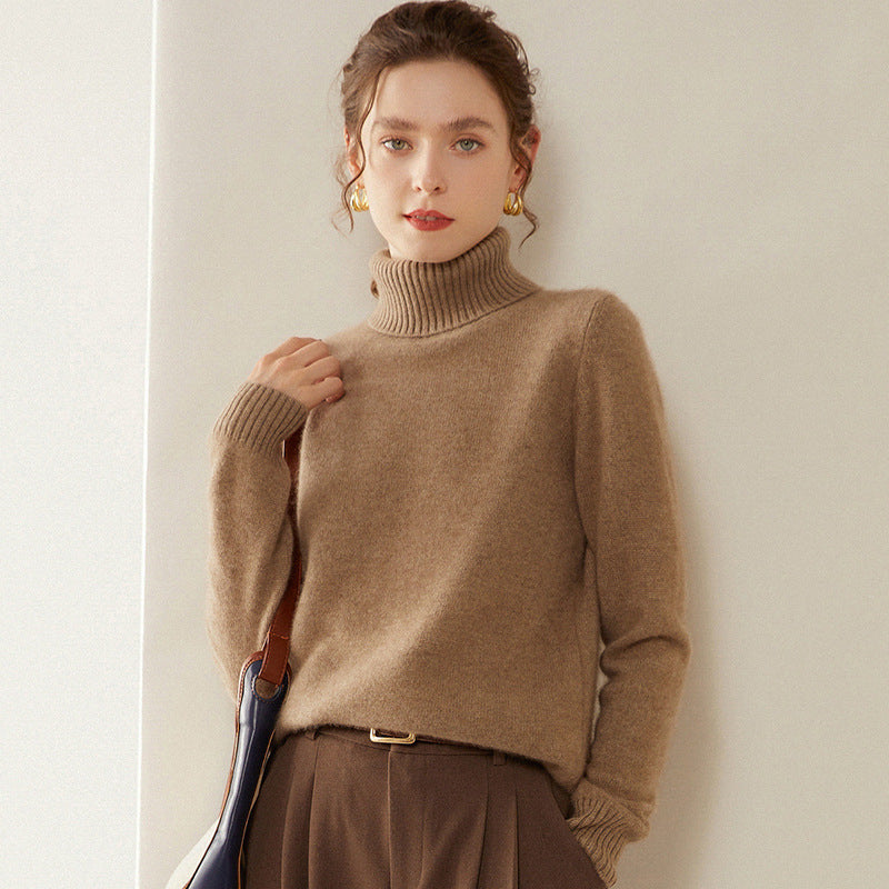 Woman wearing a Laylace camel cashmere turtleneck sweater with long sleeves and a thick ribbed knit collar.