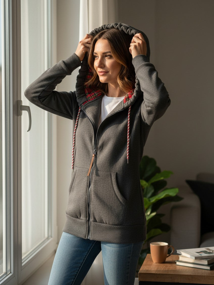 Laylace gray fleece-lined zip-up hoodie with a red plaid hood lining, worn by a woman standing by a window.