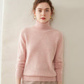 A woman wearing a soft pink Laylace thick cashmere turtleneck sweater with long sleeves and a ribbed high neckline.