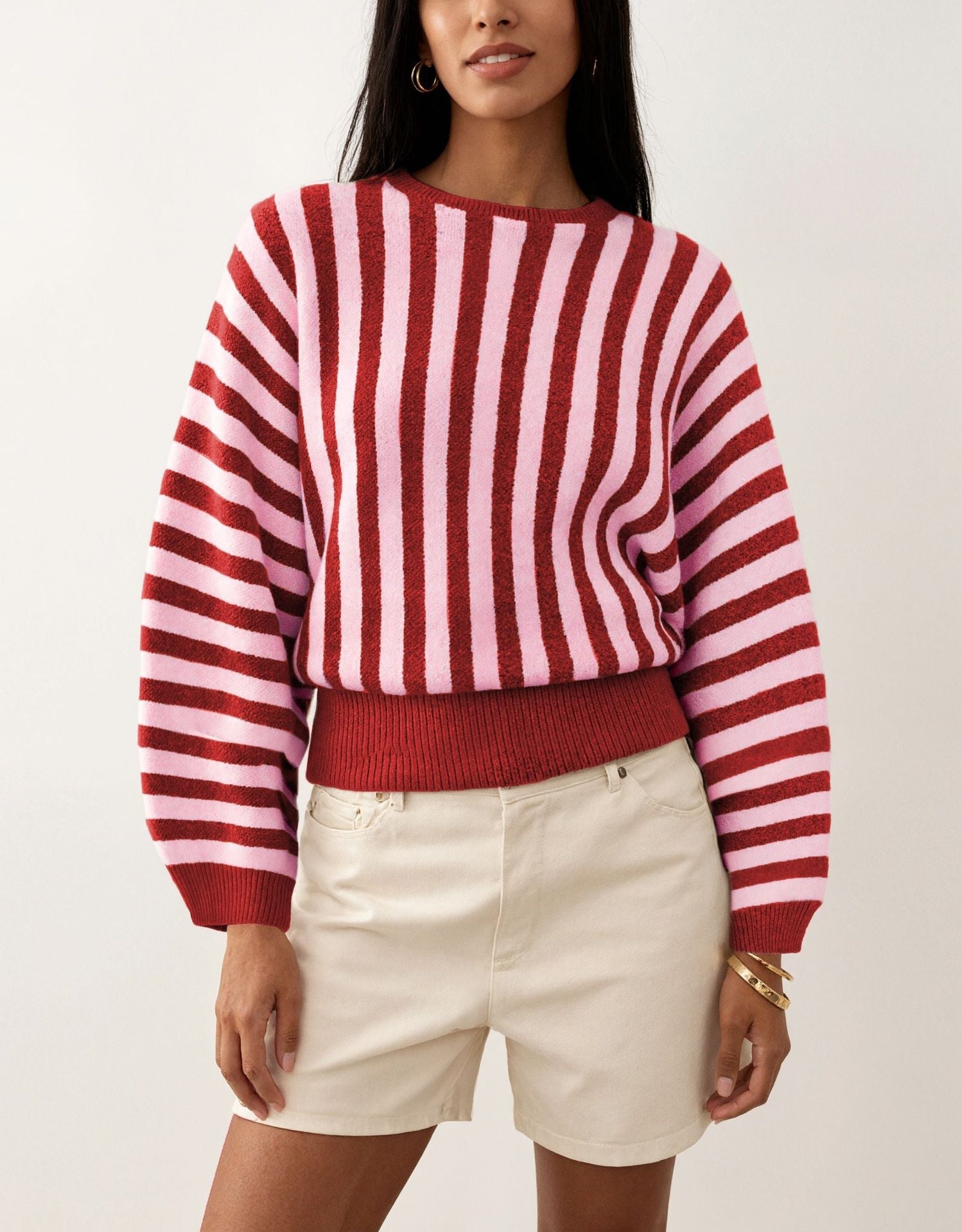 Laylace model wearing a red and pink striped long-sleeve knitted pullover sweater with a ribbed hem and cuffs