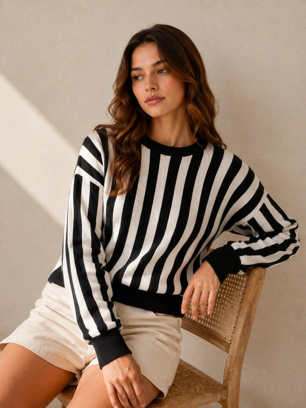 Laylace women's black and white vertical striped long-sleeve knit pullover sweater worn by a model on a chair.
