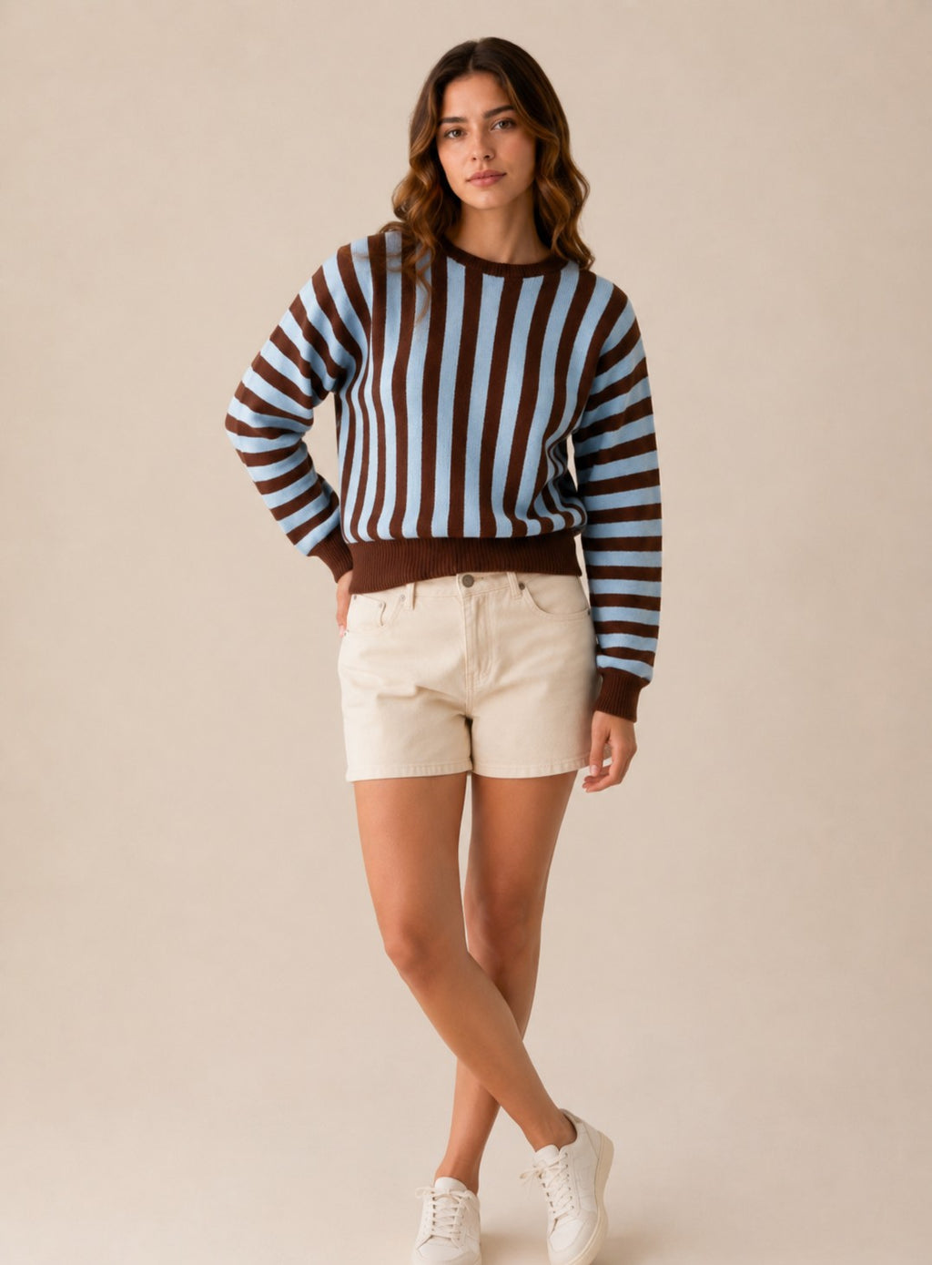 Laylace model wearing a brown and light blue vertical striped long-sleeve knit sweater with cream shorts and sneakers