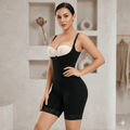 Woman wearing a black shapewear bodysuit with a white bralette in a neutral setting.