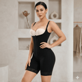Woman wearing a black shapewear bodysuit with a white bralette in a neutral setting.